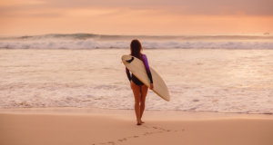 a woman with a surfboard looking to overcome her fear of the ocean