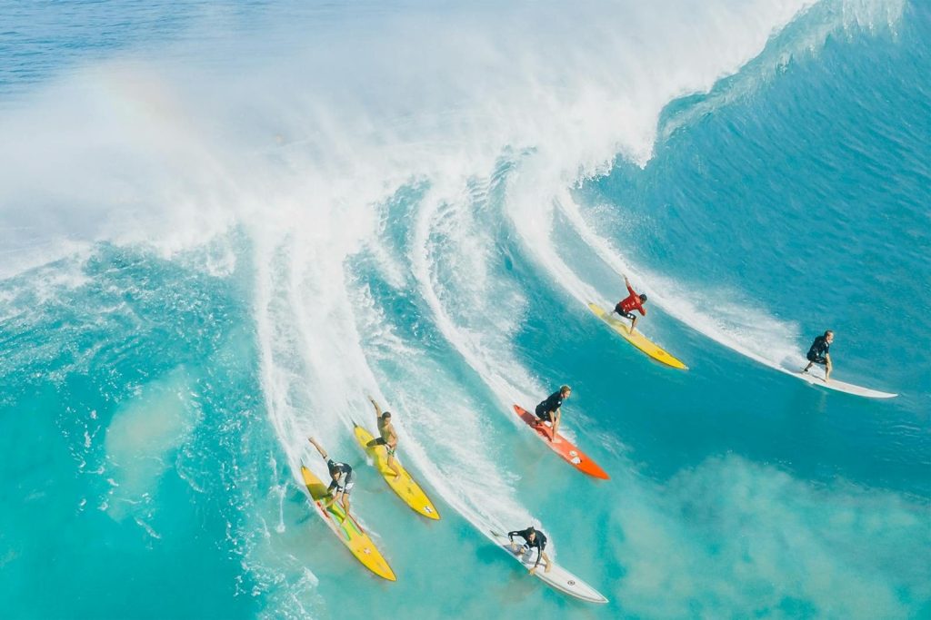 A dynamic shot of surfers riding a big wave at Waimea Bay, Hawaii. Ideal for sports and adventure themes.
